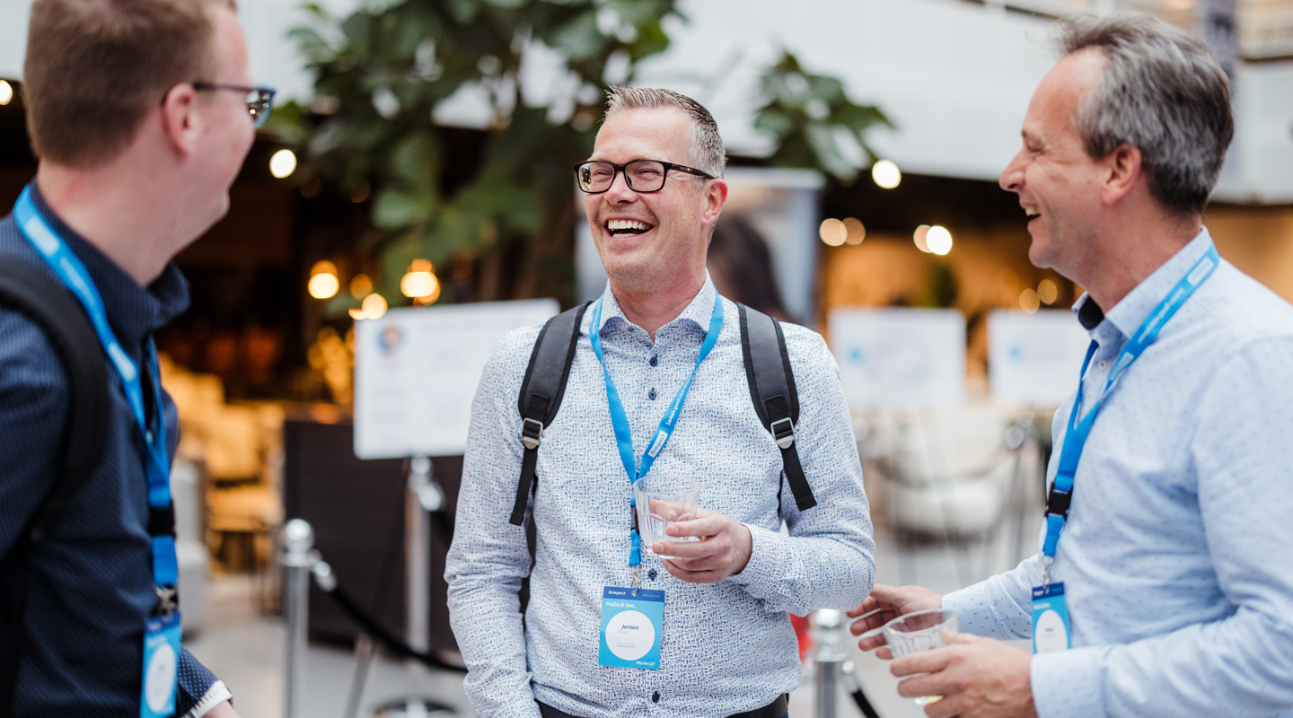 Drie mannen lachen hartelijk in gesprek met elkaar