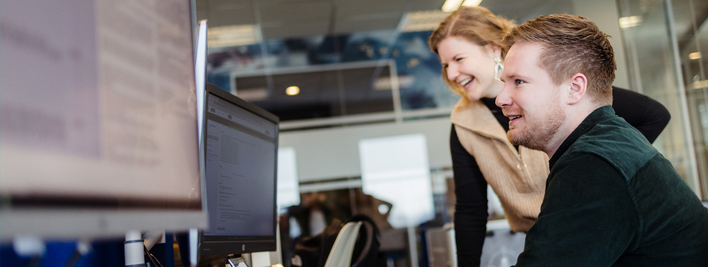 Man en vrouw kijken samen naar twee computerschermen