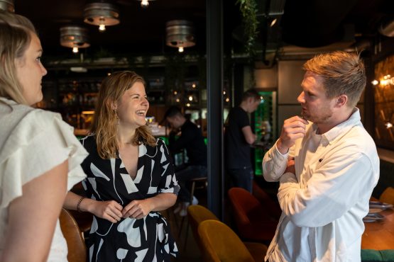 Drie mensen staan met elkaar in gesprek in restaurant