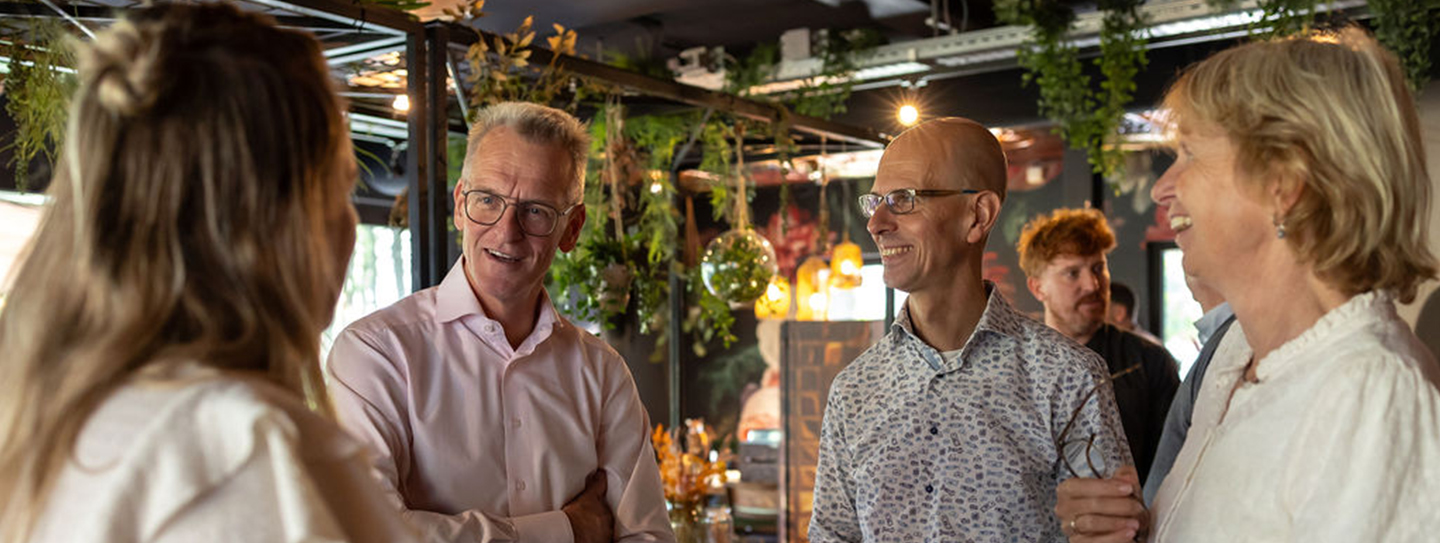 Vier mensen staan geanimeerd met elkaar te praten