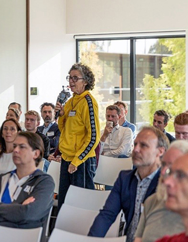 publiek met vrouw in het midden staand met microfoon